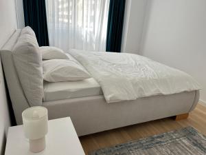 a bedroom with a bed with white sheets and a table at C-entral Apartments Bucharest with Private Parking in Bucharest