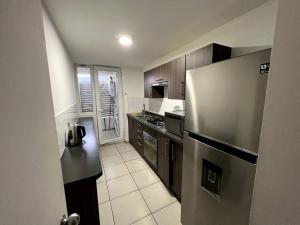 a kitchen with a stainless steel refrigerator and wooden cabinets at Cozy Apartment Near Airport, Secure, and Versatile in La Serena