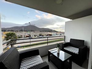 a balcony with two chairs and a table and a large window at Cozy Apartment Near Airport, Secure, and Versatile in La Serena