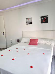 Un dormitorio con una cama blanca con flores rojas. en Apartamentos T5 Valencia, en Torrent