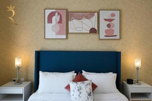 a bedroom with a blue headboard and three pictures on the wall at 1BR Oasis at Starry Yas Supernova Apartment in Abu Dhabi