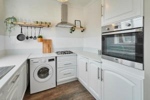 cocina con armarios blancos, lavadora y secadora en Host & Stay - Church Street, en Golborne