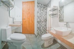 a white bathroom with a toilet and a sink at Hotel Brisas Express in San Cristóbal de Las Casas