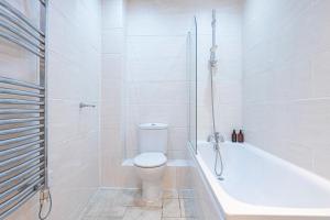 a white bathroom with a toilet and a bath tub at Turnmill Apartments in London