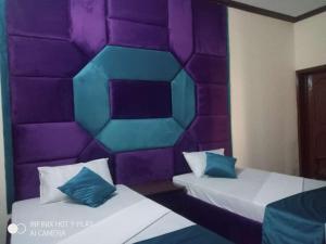 ラホールにあるNoor INN Guest Houseの紫と青の枕が備わるベッド2台が備わる客室です。