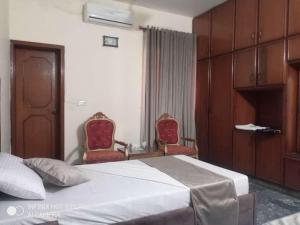 ein Hotelzimmer mit einem Bett und zwei Stühlen in der Unterkunft Noor INN Guest House in Lahore