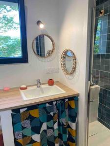 La salle de bains est pourvue d'un lavabo et de deux miroirs. dans l'établissement Maison les Acacias, à Millau