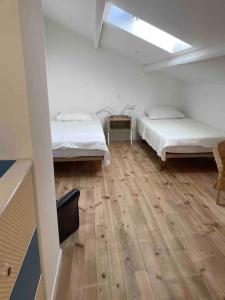 Pokój z 2 łóżkami i drewnianą podłogą w obiekcie Maison les Acacias w mieście Millau