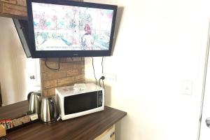 a television on top of a microwave on a counter at KippaRing Village Motel (Near Redcliffe) in Redcliffe