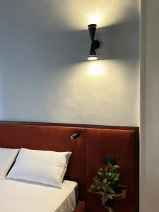 Roiss Haus Suites في ليتشي: غرفة نوم بسرير واضاءة على الحائط