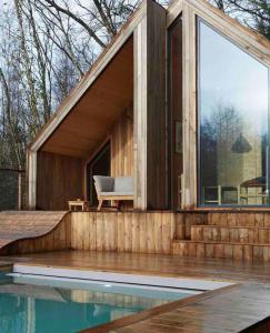 ein Haus mit einem großen Fenster neben einem Pool in der Unterkunft Casa Slow avec sa piscine chauffée au bord du lac in Les Croix Chemins