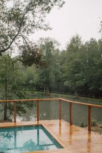 a swimming pool on a wooden deck with a fence at Casa Slow avec sa piscine chauffée au bord du lac in Les Croix Chemins
