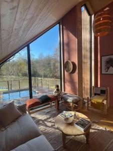 uma sala de estar com uma grande janela e um sofá em Casa Slow avec sa piscine chauffée au bord du lac em Les Croix Chemins