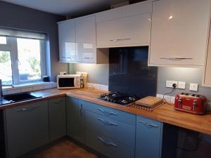 a kitchen with white cabinets and a counter with a microwave at 32 Station Road in Higham on the Hill