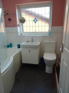 a bathroom with a toilet and a sink and a window at 32 Station Road in Higham on the Hill