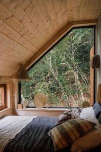 ein Schlafzimmer mit einem großen Fenster in einem winzigen Haus in der Unterkunft Casa Slow avec sa piscine chauffée au bord du lac in Les Croix Chemins