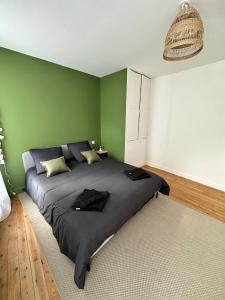 1 dormitorio con 1 cama grande y paredes verdes en Appartement cosy et moderne - 2 Chambres, en Baugé