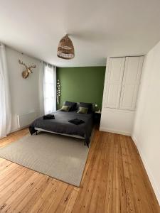 - une chambre avec un lit et un mur vert dans l'établissement Appartement T3 cosy et moderne, à Baugé