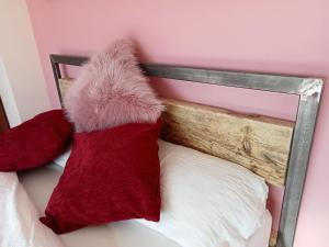 a bed with two red pillows and a wooden headboard at 32 Station Road in Higham on the Hill