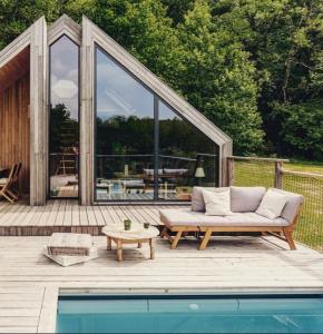 um sofá sentado num deque ao lado de uma piscina em Casa Slow avec sa piscine chauffée au bord du lac em Les Croix Chemins