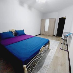 een slaapkamer met een blauw bed in een witte kamer bij жк Утеген in Alma-Ata