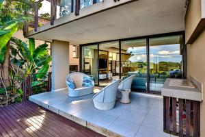 an outdoor patio with chairs and glass windows at Holiday home in Zimbali in Ballito
