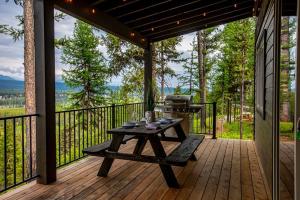 a picnic table on a deck with a grill at One of a kind views of GNP - Cabin 2 in Polebridge