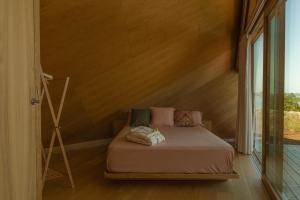 Cama en habitación con pared de madera en Cabañas de Xarás - Margarida, en Marín