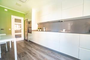 a kitchen with white cabinets and a wooden floor at Apartamento Plaza da Gándara in Narón