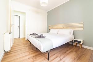 a white bed in a room with a wooden floor at Apartamento Plaza da Gándara in Narón
