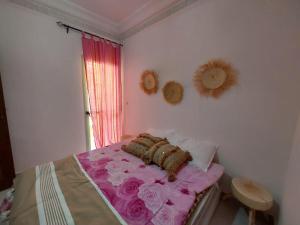 um quarto com uma cama com lençóis cor-de-rosa e uma janela em Joy Lodge em Marrakech