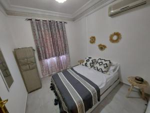 a white bedroom with a bed and a window at Joy Lodge in Marrakech