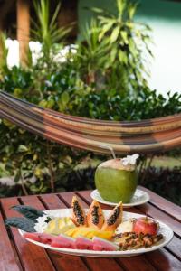 two plates of food on a table with an apple and fruit at Pousada Denada in Barra Grande