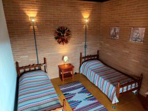 twee bedden in een kamer met een bakstenen muur bij Chalé Ganesh - O chalé é maravilhoso! in Cunha