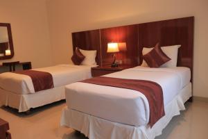 a hotel room with two beds and a lamp at Argya Santi Suite and Villas in Seminyak