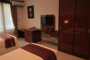 a hotel room with two beds and a television at Argya Santi Suite and Villas in Seminyak