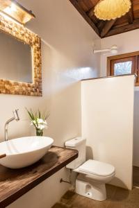 a bathroom with a sink and a toilet and a mirror at Pousada Denada in Barra Grande