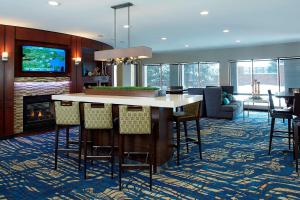 a kitchen with a bar with chairs and a fireplace at Courtyard Boston Woburn/Boston North in Woburn