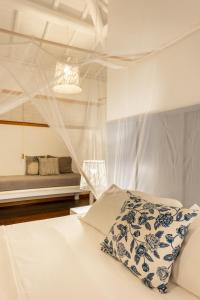 een slaapkamer met een wit bed met een blauw en wit kussen bij Pousada Denada in Barra Grande