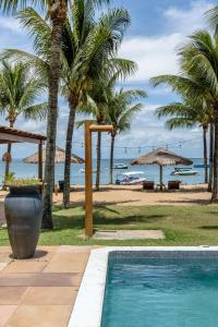a swimming pool next to a beach with palm trees at Pousada Denada in Barra Grande
