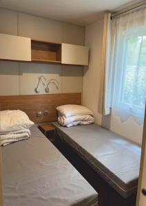 two beds in a room with a window at Grand mobile-home 45M2 au calme et au bord de mer in Saint-Brevin-les-Pins