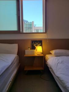 a bedroom with two beds and a table with a lamp at Well Plus Guest House in Seoul