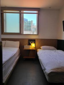 two beds in a room with a window at Well Plus Guest House in Seoul