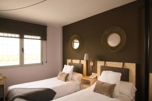 twee bedden in een kamer met twee spiegels aan de muur bij HOTEL MAUROS EL PUIG in El Puig