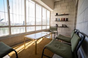 una sala de espera con mesa, sillas y ventanas en Battuta Hostel en Amán