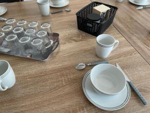 a table with cups and plates and a basket of water at Les Iris - Chambre Erable in Avanton