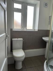a bathroom with a toilet and a sink and two windows at Spacious 2 bed flat (Free WiFi) Free Parking in Barking