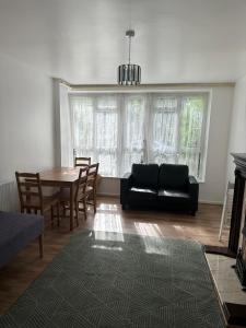 a living room with a black couch and a table at Spacious 2 bed flat (Free WiFi) Free Parking in Barking