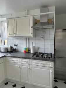 a kitchen with white cabinets and a stove at Spacious 2 bed flat (Free WiFi) Free Parking in Barking