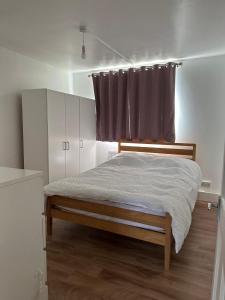 a bedroom with a bed with a window and a curtain at Spacious 2 bed flat (Free WiFi) Free Parking in Barking